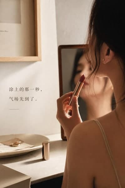 生成的情绪共鸣图:模特在梳妆台前侧身举起口红,左侧一句短文案